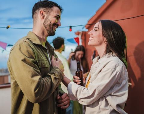 A young couple outside smiling at each other. 